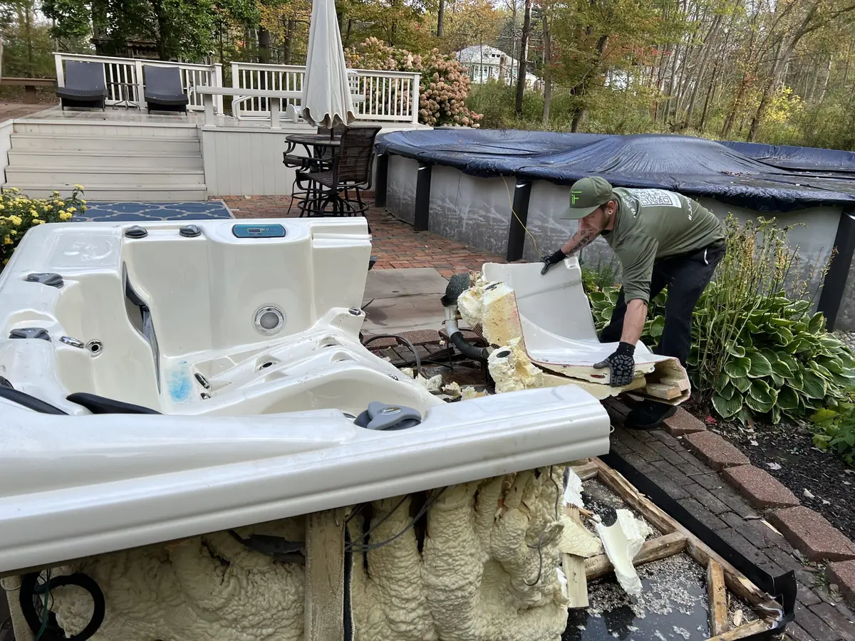 Crew member breaking up an old hot tub on a patio