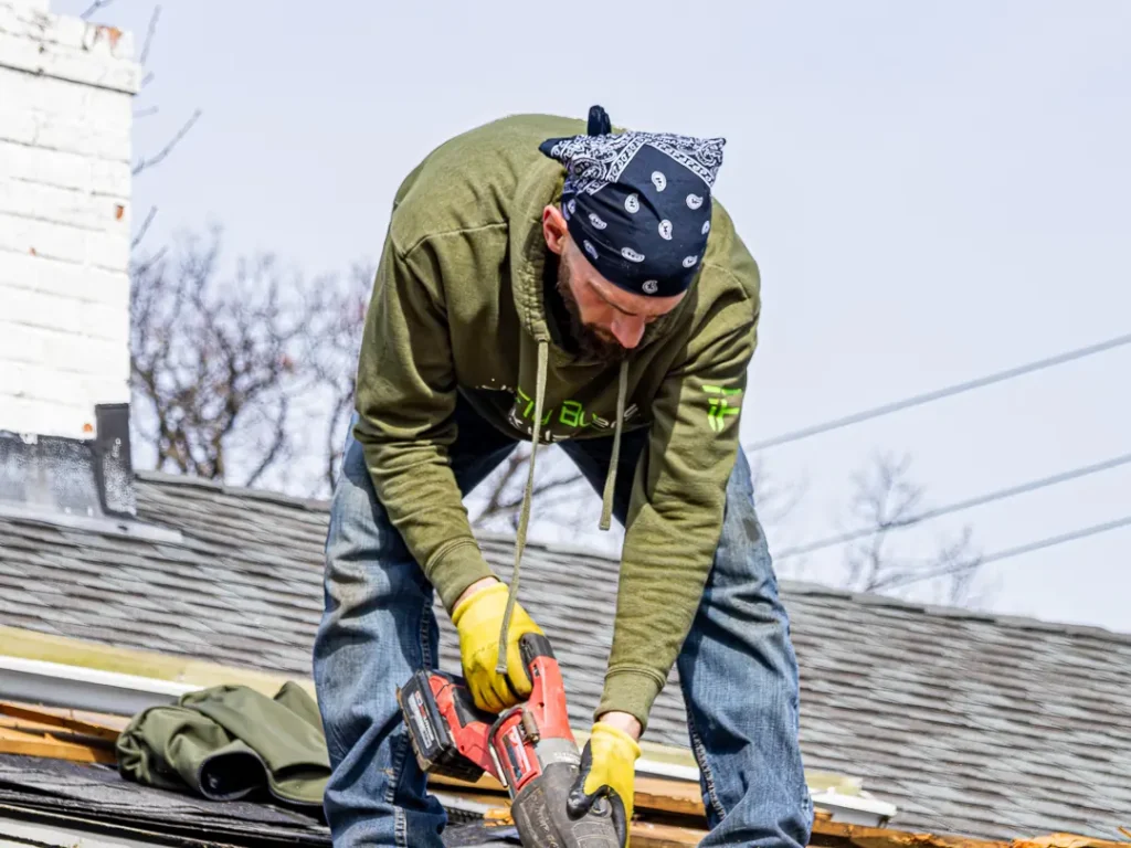 Crew member cutting out roofing and decking with a saw