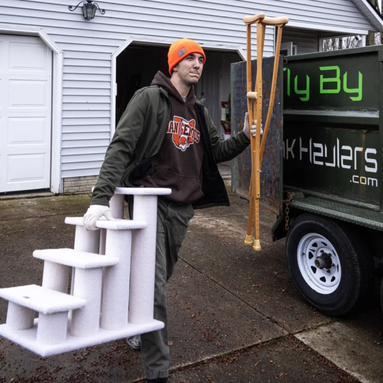 Fly By Junk Haulers crew member carrying a pet stair and crutches to the truck
