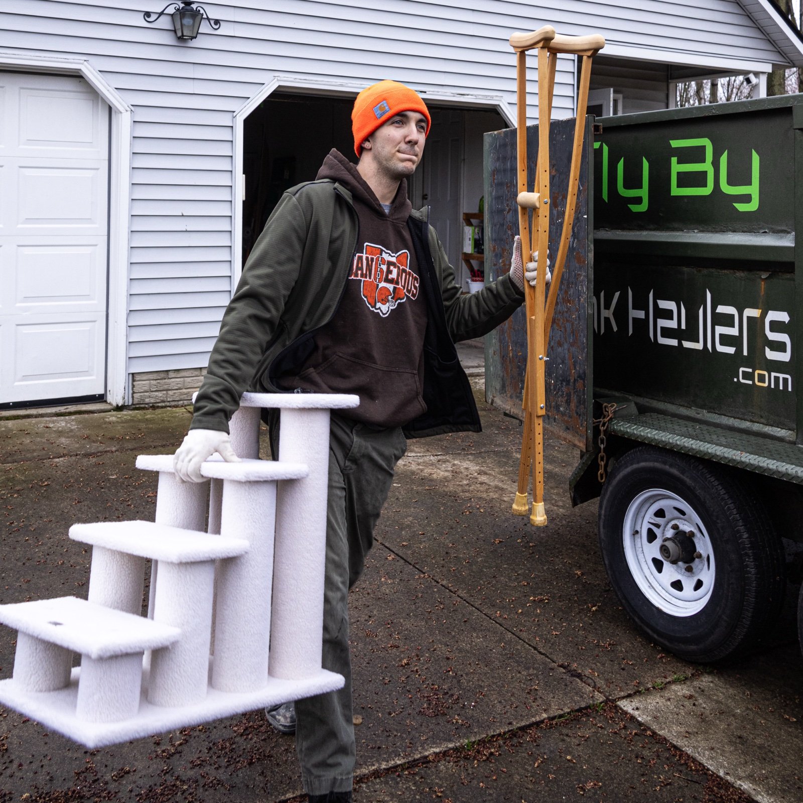 Fly By Junk Haulers crew member carrying a pet stair and crutches to the truck