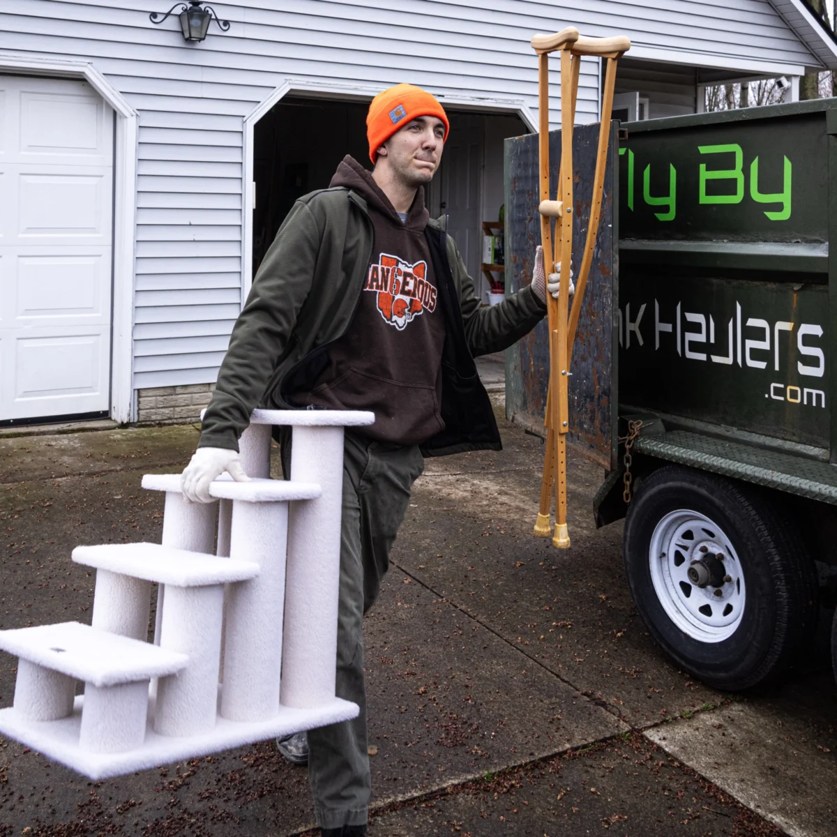 Fly By Junk Haulers crew member carrying a pet stair and crutches to the truck