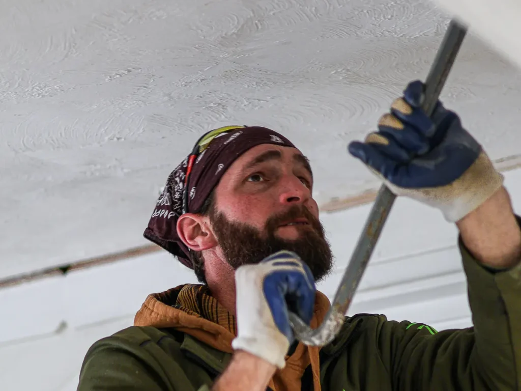Crew member prying down a ceiling with a bar