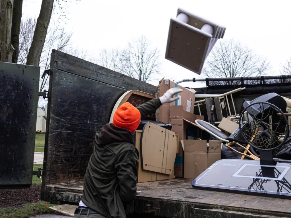 Crew member tossing furniture into a loaded Fly By dump truck