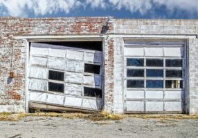 Aftermath of tornado - Commercial garage doors in vintage brick building - one is wrecked and mangled while one is still intact