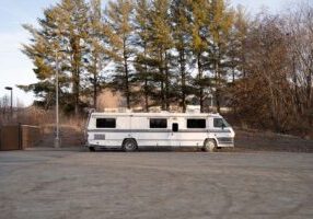 Asheville, North Carolina, United States - 5 Jan 2024:  An old white RV found behind a fast food restaurant in Asheville, North Carolina.